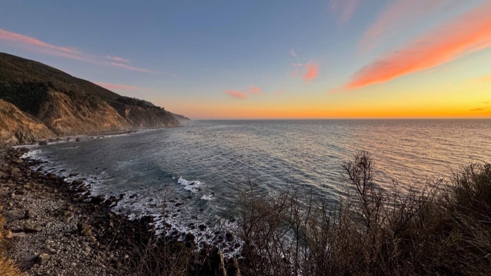 Rocky coastline at sunset with waves breaking